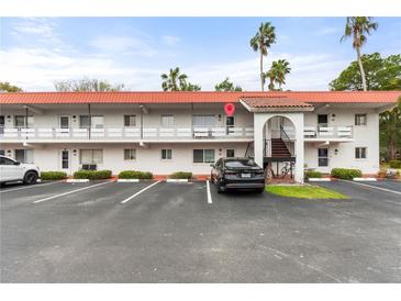 Well-maintained two-story condo building featuring palm trees and ample parking spaces at 1100 Martinique Dr # 202, Winter Haven, FL 33884