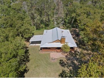 An aerial view of a house with a metal roof nestled among trees, showcasing its secluded and natural setting at 4410 Rushing Rd, Lakeland, FL 33810