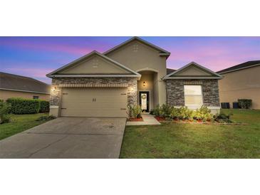 Charming single Gathering home featuring stone accents, a two-car garage, and manicured lawn at 5798 Dornich Dr, Auburndale, FL 33823