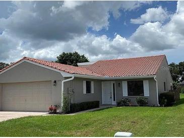 Charming single-story home featuring a red tile roof, neutral stucco, well-maintained lawn, and attached two-car garage at 692 Augusta Rd, Winter Haven, FL 33884