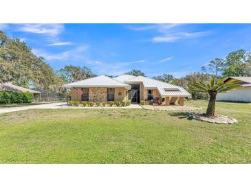 Charming single-story home featuring stone accents, a metal roof, and a well-manicured lawn at 8621 Plantation Ridge Blvd, Lakeland, FL 33809