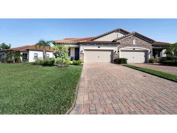 Charming home showcasing a brick driveway, a two-car garage, manicured lawn, and a stone-accented facade at 4189 Marseille Ln, Lakeland, FL 33810