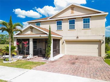 Two-story home featuring a brick driveway, a two-car garage, a screened in porch, and well-maintained landscaping at 661 Black Eagle Dr, Groveland, FL 34736