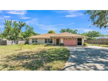 Charming single-story home with a well-maintained lawn and a pink garage door at 2954 Jennifer Dr, Lakeland, FL 33810