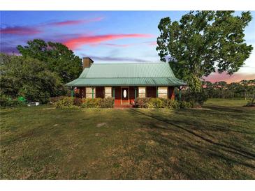 Charming single-story home featuring a green metal roof and spacious front yard with mature trees, offering classic curb appeal at 3530 Hamilton Rd, Lakeland, FL 33811
