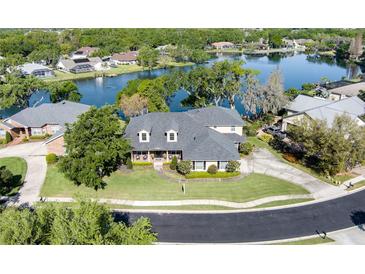 Beautiful waterfront home featuring well-manicured lawn, mature trees, and a circular driveway at 5789 Lake Victoria Dr, Lakeland, FL 33813