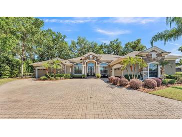 Stunning single-story home with stone accents, arched entry, mature landscaping, and paver driveway at 6774 Crescent Woods Cir, Lakeland, FL 33813