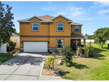 Two-story home featuring a two-car garage, and a well-manicured lawn with vibrant landscaping at 181 James Cir, Lake Alfred, FL 33850