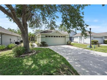 Charming home featuring an attached garage, lush green lawn, and mature trees providing shade on a sunny day at 4139 Cobblestone Dr, Lakeland, FL 33813