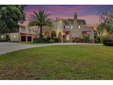 Stunning two-story stucco home featuring an arched entry, lush lawn, mature landscaping, and detached garage at 845 E Edgewood Dr, Lakeland, FL 33803