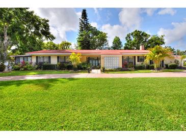 Charming single-story home with a red roof, lush landscaping, and a brick driveway at 1407 Easton Dr, Lakeland, FL 33803