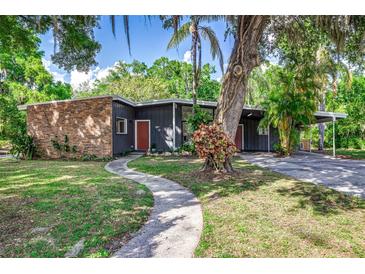 Stylish single-story home with a brick accent wall, a red front door, mature landscaping, and a winding walkway at 1604 Sylvester Rd, Lakeland, FL 33803