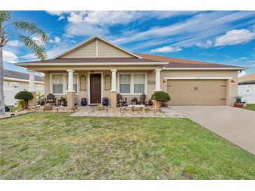Charming single-story home with a well-manicured lawn and inviting front porch seating area, perfect for relaxing at 1925 Binnacle St, Kissimmee, FL 34744