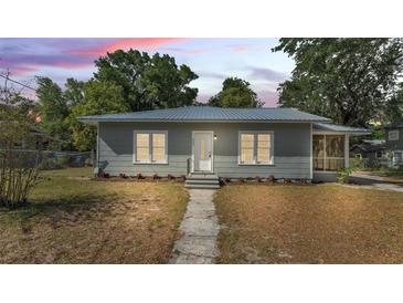 Charming single-story home featuring gray siding, a matching metal roof, and well-kept landscaping at 2203 Avenue F Nw, Winter Haven, FL 33880