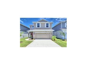 Charming two-story home with a well-manicured lawn, attached two-car garage, and neutral-colored exterior at 2303 Brassie Ct, Winter Haven, FL 33884