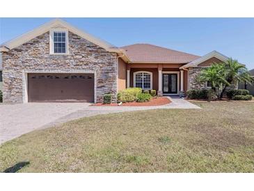 Beautiful single-story home boasts a stone facade, brown siding, well-manicured lawn, and a two-car garage at 5612 Vintage View Blvd, Lakeland, FL 33812