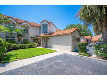 Charming home featuring a red tile roof, a well-manicured lawn, and a private garage, under a clear blue sky at 71 Sunset View Dr # 71, Winter Haven, FL 33884