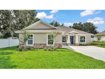 Beautiful single-story home featuring a well-manicured lawn, stone accents, and a stylish, modern design at 803 Allison Place, Bartow, FL 33830