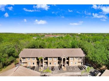 A bright two-story apartment building with ample parking and a lush green background at 8838 Coral Palms Ct # A, Kissimmee, FL 34747