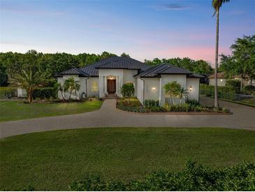 Stunning home featuring mature landscaping, circular driveway, and a metal roof at 13137 Lake Butler Blvd, Windermere, FL 34786