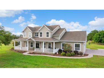 Charming two-story home with a welcoming wrap-around porch and meticulously manicured lawn at 150 Berkley Knights Dr, Auburndale, FL 33823