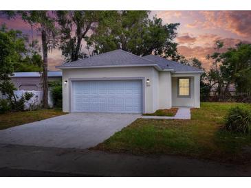 Charming single-story home featuring a two-car garage, neutral paint, and landscaped front yard under a colorful evening sky at 1850 Martin Luther King, Jr. E Blvd, Bartow, FL 33830