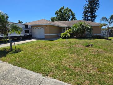 Charming ranch home with an attached garage, lush lawn, palms, and an RV parked in the driveway at 7818 Lewis Rd, Lakeland, FL 33810