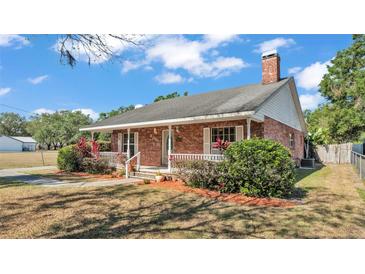 Charming brick home featuring a cozy front porch and landscaped yard at 1055 Sunset Ave, Bartow, FL 33830