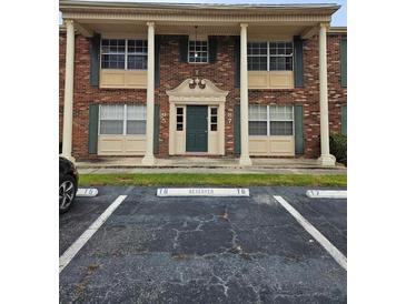 Brick building with columns, dark green shutters, reserved parking spaces and a black car on the side at 1920 E Edgewood Dr # T6, Lakeland, FL 33803