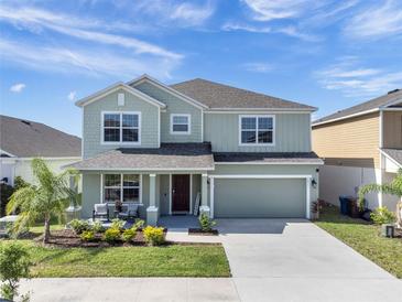 Two-story home featuring a front porch, well-maintained lawn, and an attached two car garage at 871 Fillmore Ct, Davenport, FL 33837