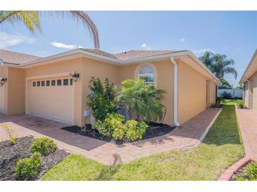 Charming home with manicured landscaping, a paver walkway, and a beige-colored exterior at 1620 Linz Ct, Winter Haven, FL 33884