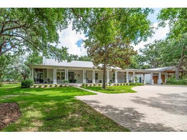 Charming single-story home with a metal roof, wraparound porch, and brick driveway at 2115 W Pipkin Rd, Lakeland, FL 33811