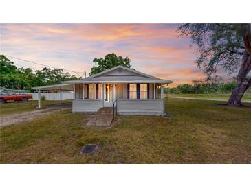 Charming single-story home featuring a cozy screened porch, carport, and a picturesque sunset backdrop at 410 Orange St, Bradley, FL 33835