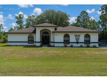 Charming single-story home boasts a well-manicured front lawn, arched entryway, and neutral-toned exterior at 5218 Parkland Ct, Lakeland, FL 33811