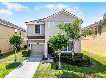 Charming two-story home featuring a well-manicured lawn, garden, and driveway leading to an attached single-car garage at 8929 Sugar Palm Rd, Kissimmee, FL 34747