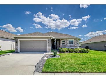 Charming single-story home featuring a two-car garage, stone accents, and beautifully landscaped front yard at 1297 Pintail Pl, Lakeland, FL 33813