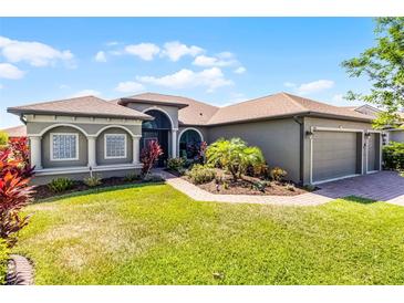 Charming single-story home features a lush lawn, meticulous landscaping, and a three car garage at 1394 Oakmont Dr, Winter Haven, FL 33884