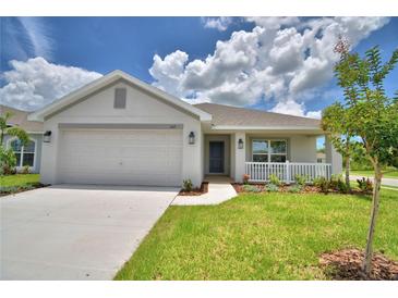 Charming single-story home featuring a two-car garage, landscaped front yard, and covered porch at 1517 Leamington Ln, Winter Haven, FL 33884