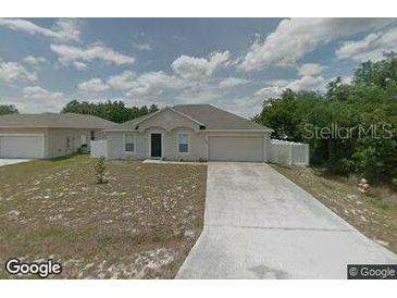 Charming single-story home with a two-car garage and a long driveway in a suburban setting at 1908 Manatee Dr, Kissimmee, FL 34759