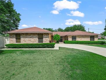 Charming brick home featuring a well-manicured lawn, mature landscaping, and an inviting driveway at 3002 Helms Dr, Auburndale, FL 33823