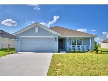 Charming single-story home with a two-car garage, covered porch, and a well-maintained lawn under a clear blue sky at 580 Jett Ln, Davenport, FL 33837
