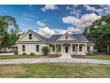 Charming single-Gathering home with a well-manicured lawn, a blue front door and a welcoming front porch at 2070 W Lake Hamilton Dr, Winter Haven, FL 33881