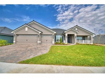 Beautiful single-Gathering home featuring a well-manicured lawn and a three-car garage with a brick paver driveway at 5220 Tennessee Ridge Ct, Auburndale, FL 33823