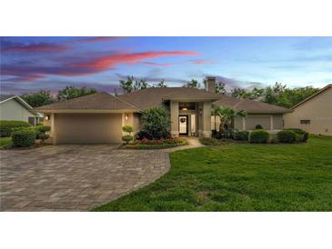 Charming single-story home with landscaped yard and brick-paved driveway under a colorful sunset at 146 Woodside Dr, Lakeland, FL 33813