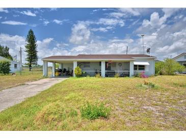 Charming single-story home with a covered carport and quaint front porch, set against a cloudy sky at 224 Raymond Ave, Frostproof, FL 33843