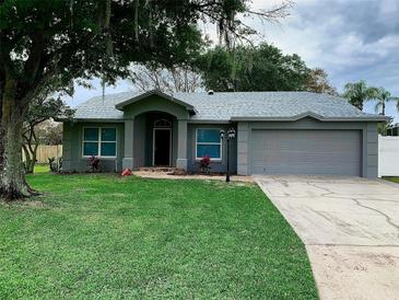 Charming single-story home with a well-maintained lawn, attached two-car garage, and mature trees at 676 Jessanda Cir, Lakeland, FL 33813