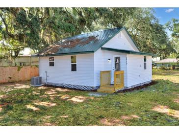 Charming cottage-style home featuring a green metal roof and white siding, surrounded by mature trees and a well-maintained yard at 6949 2Nd St, Mulberry, FL 33860