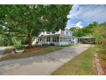 Charming two-story home with a covered front porch, lush landscaping, and a long driveway at 716 S Franklin Pl, Lakeland, FL 33815