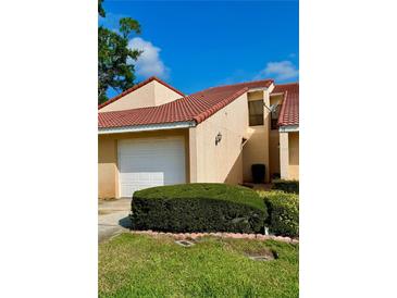 Charming villa featuring a red tile roof, attached garage and manicured landscaping on a sunny day at 733 Carpenters Way # 36, Lakeland, FL 33809