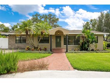 Charming single-story home with brick walkway, lush lawn, beautiful tropical landscaping, and inviting front entrance at 865 E Mann Rd, Bartow, FL 33830